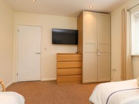 A bedroom with a TV, wardrobe, and chest of drawers at Gelli - Morfa Nefyn in Morfa Nefyn
