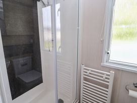 A bathroom with a shower, toilet, and a heated towel rail at Stag Lodge, Caravan 70 Great Yarmouth
