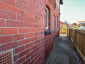 A pathway alongside a red brick wall with a plant pot at Falcon Luxe in Whitby