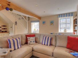 A living room with a sofa and decorative pillows at Half Moon Cottage in Lyme Regis