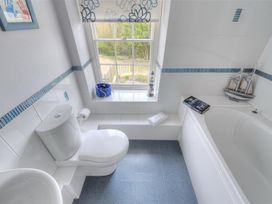 A bathroom with a toilet, bathtub, and a window at Half Moon Cottage in Lyme Regis