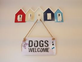 A wall with coat hooks and a dogs welcome sign at Half Moon Cottage in Lyme Regis