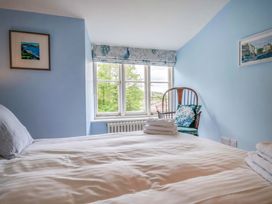 A bedroom with a bed and chair at Half Moon Cottage in Lyme Regis