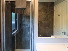 A bathroom with a shower, towel, mirror, and door at Costapacket in Grasmere 12, White Cross Bay near Windermere