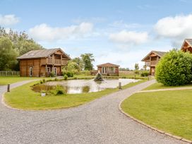 An outdoor view with cabins around a pond at Pear Tree, Carlton Miniott near Thirsk