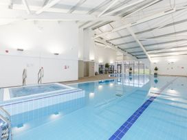 A swimming pool area with a hot tub and seating at Pear Tree Carlton Miniott near Thirsk