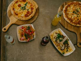 A pizza and fries served on wooden boards with sodas at Pear Tree Carlton Miniott near Thirsk