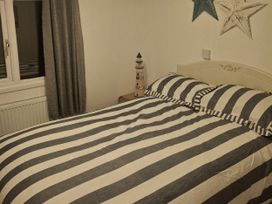 A bedroom with a striped bed and lighthouse decor at Hafan y Mor Haven - Holiday Accommodation 10104, Pwllheli