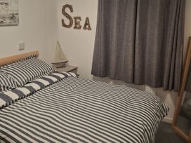 A bedroom with a striped bed and decorative elements at Hafan y Mor Haven - Holiday Accommodation 10104, Pwllheli