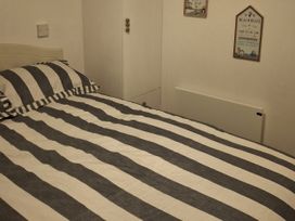 A bedroom with a striped bed and wardrobe at Hafan y Mor Haven - Holiday Accommodation 10104, Pwllheli