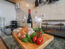 A kitchen counter with bread, tomatoes, wine, and glasses at The Studio on the Crescent in Whitby