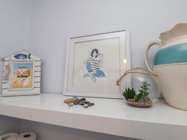A shelf with a picture frame, decorative house, ceramic jug, and a plant at The Studio on the Crescent in Whitby