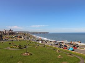 A view of the coastline with cars on the road and grass at The Studio on the Crescent Whitby