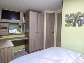 A bedroom with a bed, wardrobe, and television at Wild Duck Holiday Park in Belton, Norfolk