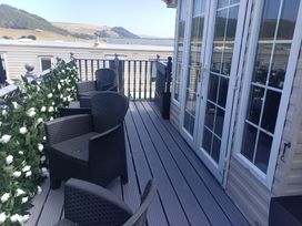A balcony with chairs and sliding doors at Clarach Bay Holiday Village - Holiday Accommodation 10536 Aberystwyth