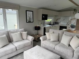 A living room with a sofa and kitchen area at Primrose Valley Holiday Park - Holiday Accommodation 10790, Filey