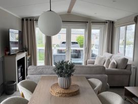A living room with a dining table and television at Primrose Valley Holiday Park - Holiday Accommodation 10790 in Filey