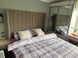 A bedroom with a bed and mirror at Primrose Valley Holiday Park - Holiday Accommodation 10790 Filey