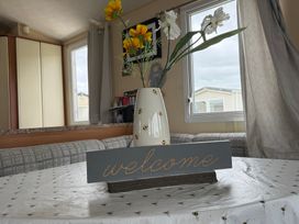 A dining room with a welcome sign and flowers in a vase at Cala Gran Holiday Park - Holiday Accommodation 10830 Fleetwood