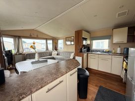 A living room with a kitchen area featuring a couch and kitchen appliances at Cala Gran Holiday Park - Holiday Accommodation 10830, Fleetwood