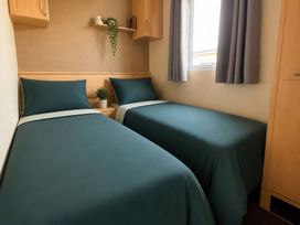 A bedroom with two single beds and a shelf with a plant at Cala Gran Holiday Park - Holiday Accommodation 10830 Fleetwood