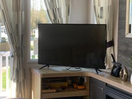 A living room with a television on a shelf at Kiln Park Holiday Park - Holiday Accommodation 1142 Tenby