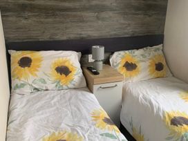 A bedroom with two beds and a bedside table at Kiln Park Holiday Park - Holiday Accommodation 1142 Tenby