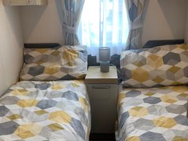 A bedroom with two single beds and a bedside table at Kiln Park Holiday Park - Holiday Accommodation 1142 Tenby