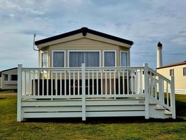 a holiday home with a deck and sliding glass doors at Silver Sands Holiday Park - Holiday Accommodation 11481 in Lossiemouth