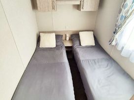 a room with two single beds and a nightstand at Silver Sands Holiday Park - Holiday Accommodation 11481 Lossiemouth