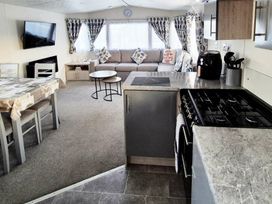 a living room and kitchen area with a sofa, dining table, and kitchen appliances at Silver Sands Holiday Park - Holiday Accommodation 11481 in Lossiemouth