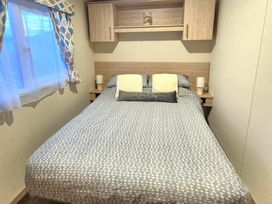a bedroom with a double bed and bedside tables at Silver Sands Holiday Park - Holiday Accommodation 11481 in Lossiemouth
