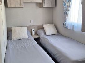 a bedroom with two single beds and a bedside table at Silver Sands Holiday Park - Holiday Accommodation 11481 in Lossiemouth