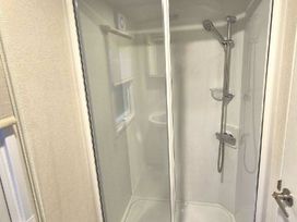 a shower enclosure with glass doors and a showerhead at Silver Sands Holiday Park - Holiday Accommodation 11481 Lossiemouth