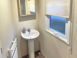 a bathroom with a sink, mirror, and window at Silver Sands Holiday Park - Holiday Accommodation 11481 in Lossiemouth