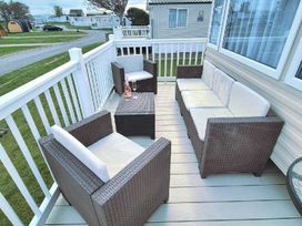 a deck with brown wicker furniture and a table at Silver Sands Holiday Park - Holiday Accommodation 11481 Lossiemouth
