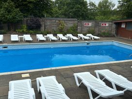 An outdoor pool area with loungers at Penlan Holiday Park - Holiday Accommodation 11792 Cenarth