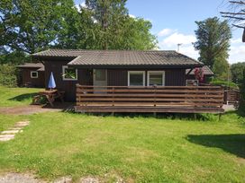 A cabin with a deck and an umbrella at Penlan Holiday Park - Holiday Accommodation 11792 in Cenarth