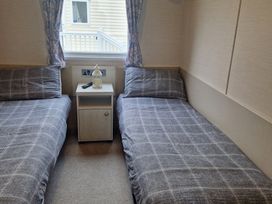 A bedroom with two beds and a bedside table at Craig Tara Holiday Park - Holiday Accommodation 12278, Ayr
