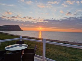 A view of a sunset over the sea with a table and chairs at Craig Tara Holiday Park - Holiday Accommodation 12278, Ayr