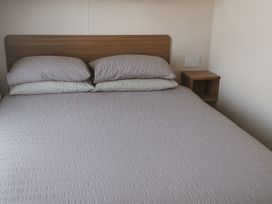 A bed with pillows and a bedside table at Freshwater Beach Holiday Park - Holiday Accommodation 12281, Burton Bradstock