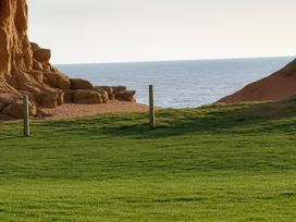 a grassy area with wooden posts near a cliff and ocean at Freshwater Beach Holiday Park - Holiday Accommodation 12281 in Burton Bradstock