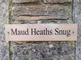 A wooden sign that reads Maud Heath's Snug on a stone wall at Maud Heath's Snug, East Thytherton