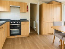 A kitchen with cabinets and stove at Lyons Sunnysands Holiday Park - Holiday Accommodation 12581 Barmouth