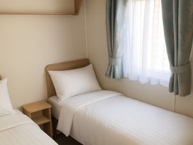 A bedroom with two single beds and a window at Lyons Sunnysands Holiday Park - Holiday Accommodation 12581 Barmouth