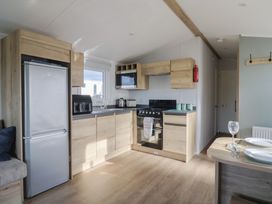 A kitchen with appliances and dining table at Littlesea Holiday Park - Holiday Accommodation 13127, Weymouth