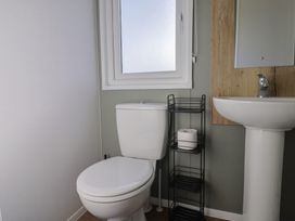 A bathroom with a toilet, sink and window at Littlesea Holiday Park - Holiday Accommodation 13127 Weymouth