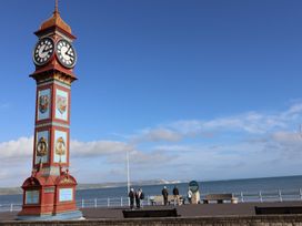 A clock tower near the ocean with people on a promenade at Littlesea Holiday Park - Holiday Accommodation 13127 Weymouth