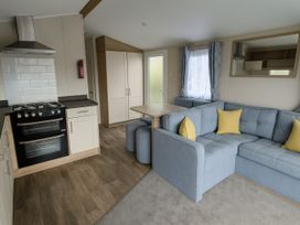 a living room with a sofa and table near a kitchen area at Lyons Sunnysands Holiday Park - Holiday Accommodation 13733 Barmouth