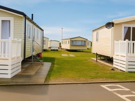 An outdoor area with mobile homes and green grass at Lyons Sunnysands Holiday Park - Holiday Accommodation 13733, Barmouth